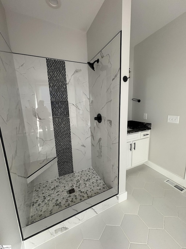 bathroom featuring a tile shower, tile patterned floors, and vanity