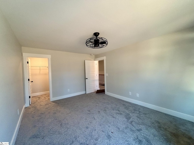 unfurnished bedroom featuring a walk in closet, a closet, and carpet floors