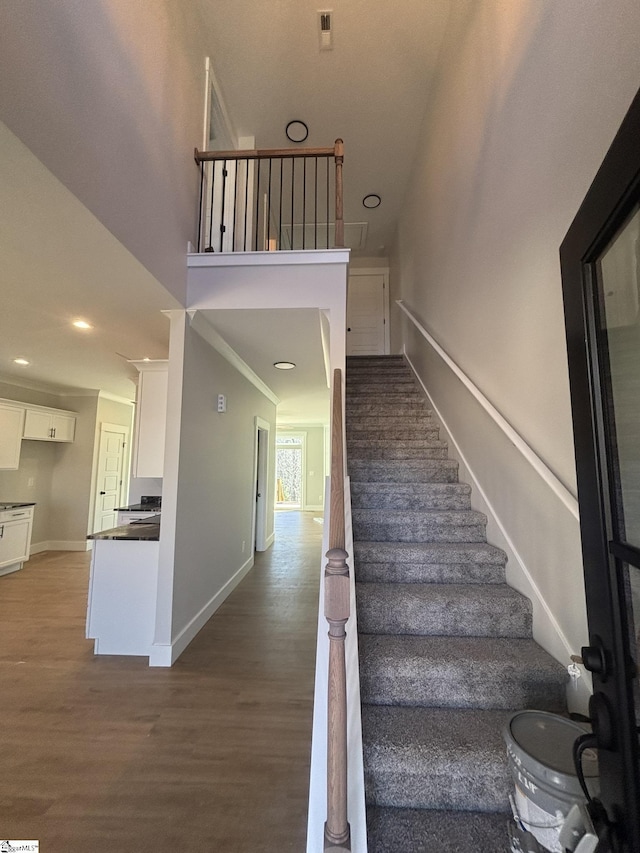 staircase featuring wood-type flooring and ornamental molding