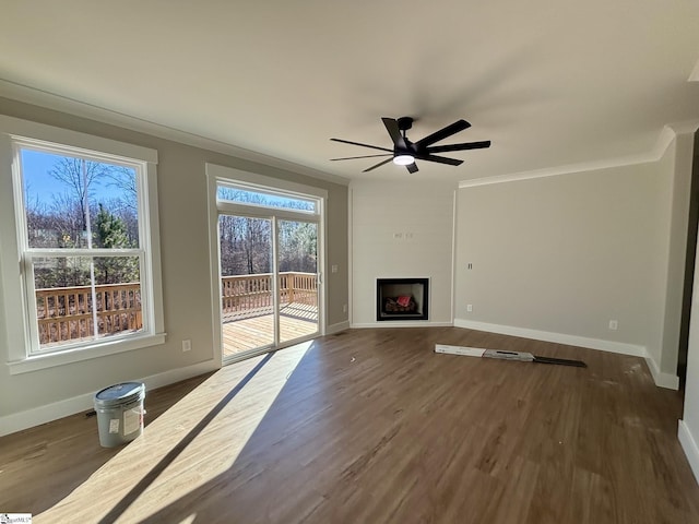 unfurnished living room with a fireplace, ceiling fan, ornamental molding, and dark wood-type flooring