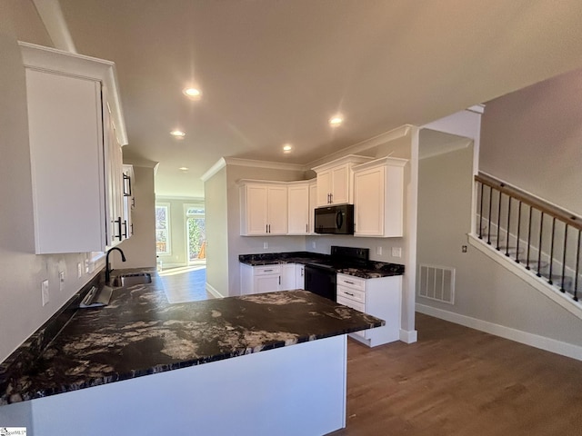 kitchen with white cabinetry, kitchen peninsula, wood-type flooring, black appliances, and ornamental molding