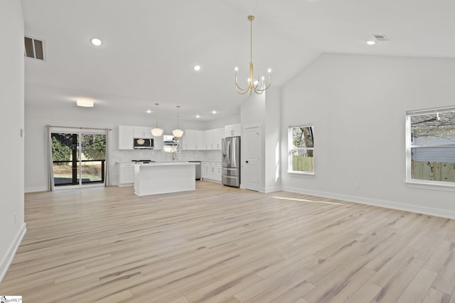 unfurnished living room with a notable chandelier, light wood-type flooring, and high vaulted ceiling