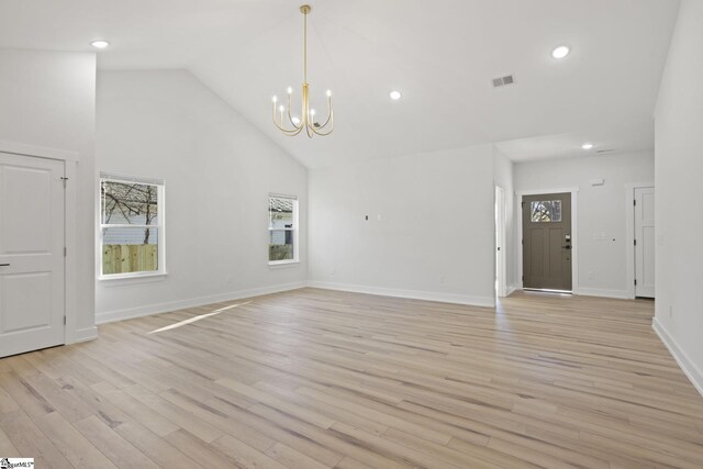 unfurnished living room featuring a chandelier, high vaulted ceiling, and light hardwood / wood-style flooring