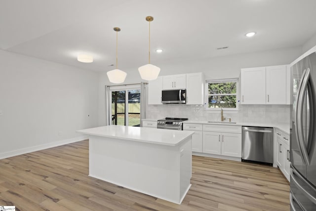 kitchen featuring sink, appliances with stainless steel finishes, tasteful backsplash, decorative light fixtures, and white cabinetry