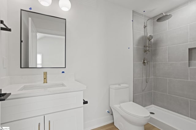 bathroom with a tile shower, vanity, and toilet