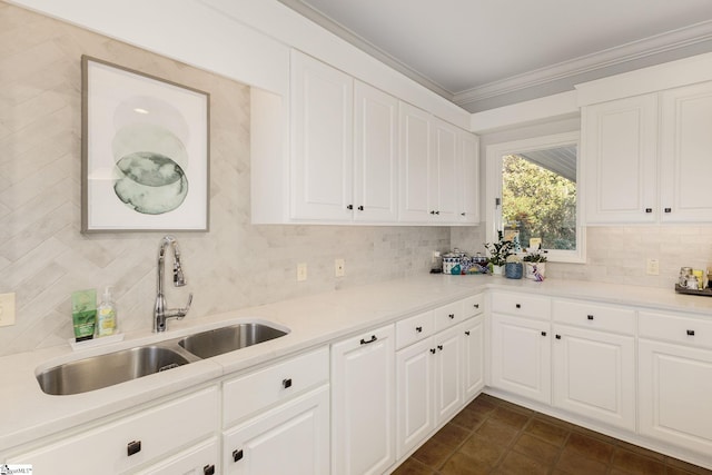 kitchen with backsplash, ornamental molding, sink, dark tile patterned flooring, and white cabinets