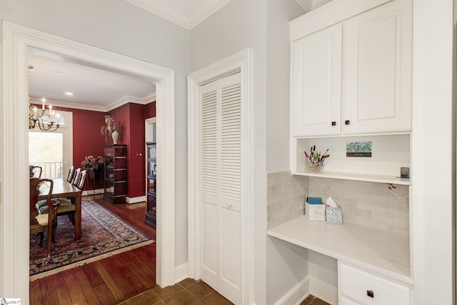 corridor with dark hardwood / wood-style flooring, a chandelier, and ornamental molding