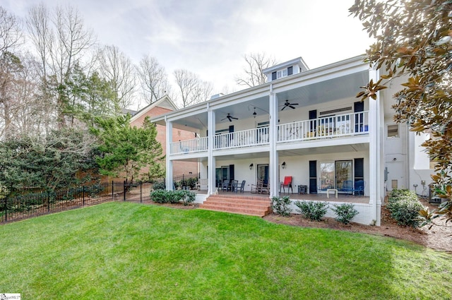 rear view of property with covered porch, ceiling fan, a balcony, and a yard