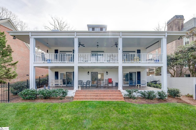 back of property featuring a lawn, ceiling fan, a patio area, and a balcony