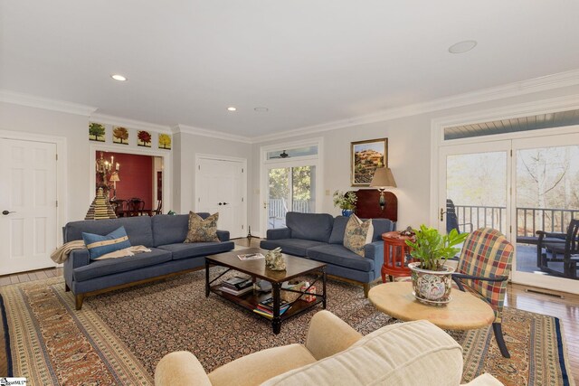 living room with an inviting chandelier, wood-type flooring, and ornamental molding