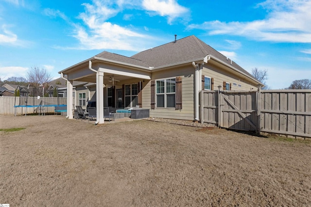 back of property with ceiling fan, a trampoline, and a patio