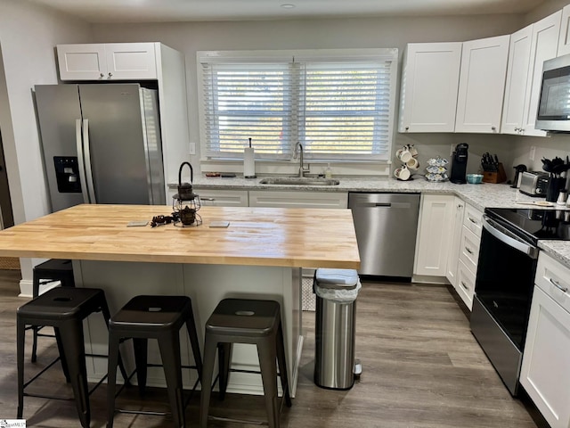 kitchen with white cabinets, a kitchen breakfast bar, stainless steel appliances, and butcher block counters