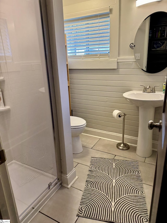 bathroom with tile patterned floors, toilet, and a shower