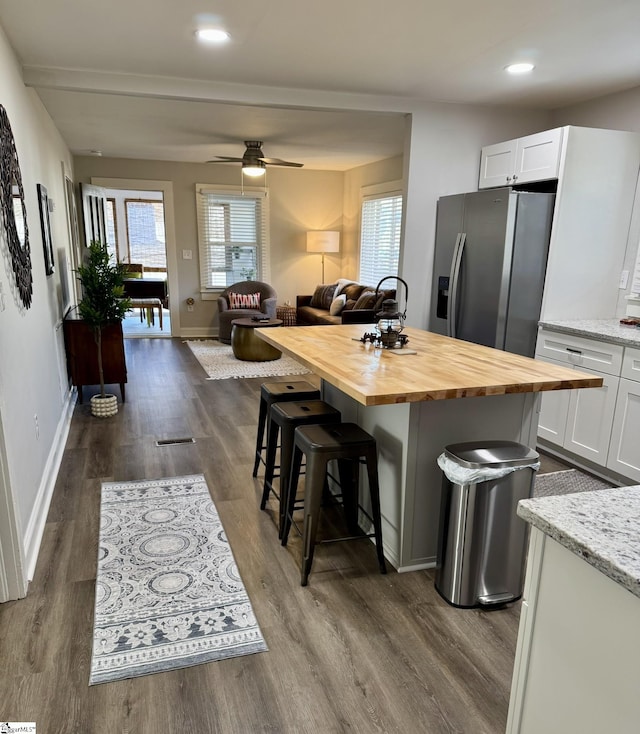 kitchen featuring wooden counters, white cabinets, stainless steel refrigerator with ice dispenser, a kitchen island, and a kitchen bar