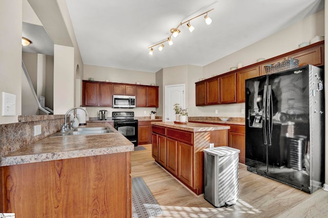 kitchen with black appliances, kitchen peninsula, sink, and light hardwood / wood-style flooring