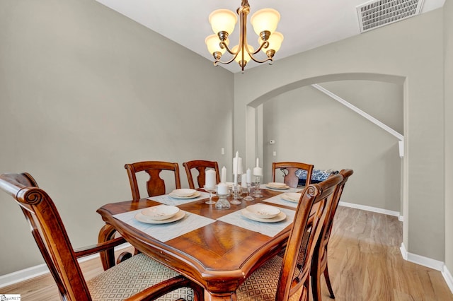 dining area with light hardwood / wood-style floors and a notable chandelier