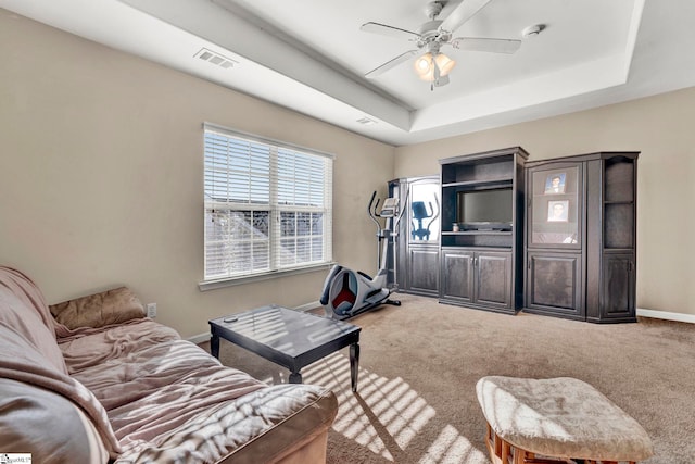 living room featuring a raised ceiling, ceiling fan, and carpet