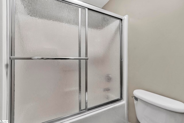 bathroom featuring combined bath / shower with glass door and toilet