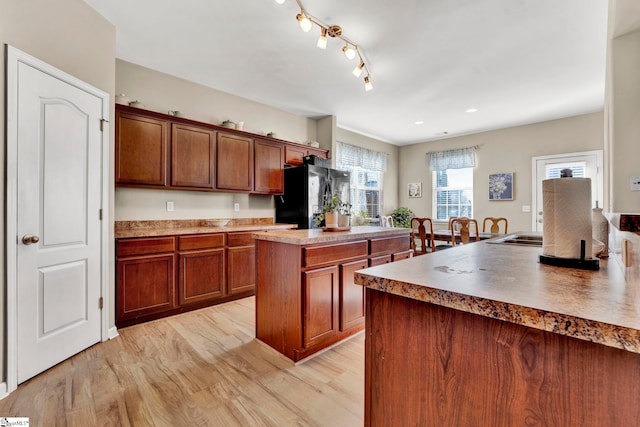 kitchen with black refrigerator, a kitchen island, and light wood-type flooring