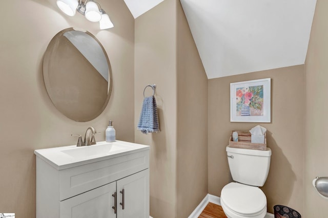 bathroom featuring wood-type flooring, vanity, toilet, and vaulted ceiling