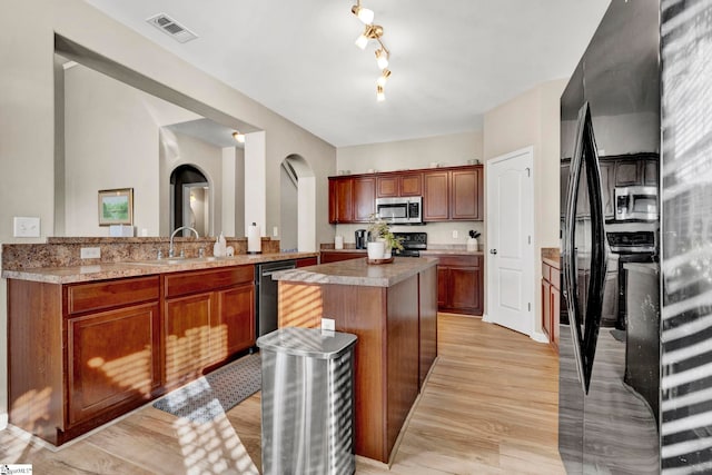 kitchen featuring kitchen peninsula, sink, black appliances, light hardwood / wood-style floors, and a kitchen island