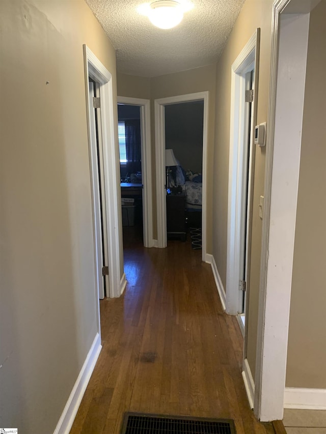 corridor with dark hardwood / wood-style floors and a textured ceiling