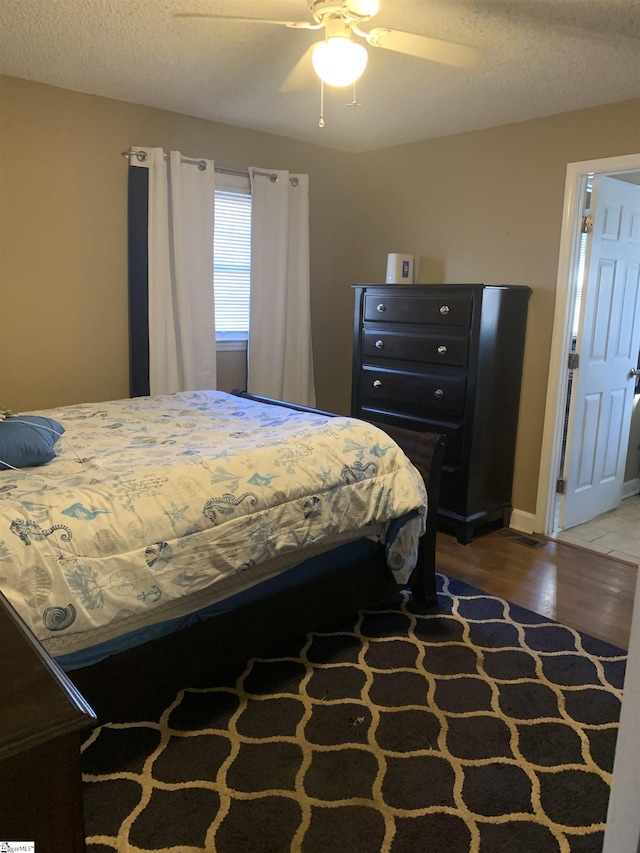 bedroom featuring hardwood / wood-style floors, a textured ceiling, and ceiling fan