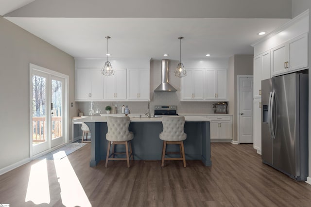 kitchen featuring pendant lighting, white cabinetry, wall chimney range hood, and appliances with stainless steel finishes