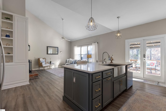 kitchen featuring sink, stainless steel dishwasher, vaulted ceiling, gray cabinets, and a kitchen island with sink