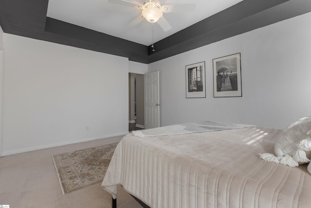 carpeted bedroom with ceiling fan and a tray ceiling