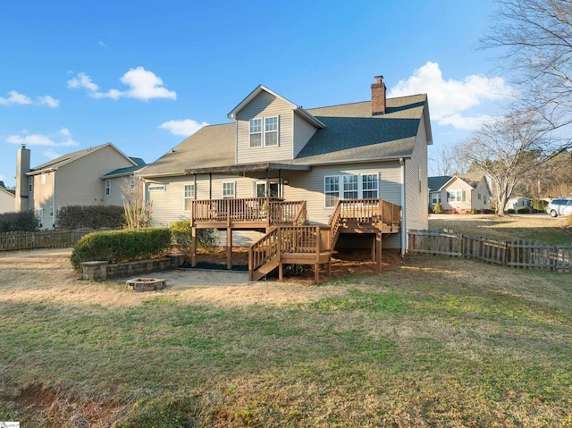 rear view of property with a lawn, a deck, and an outdoor fire pit