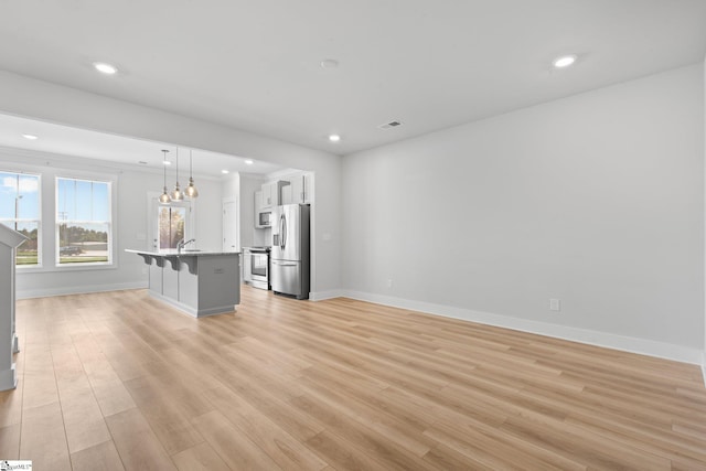 unfurnished living room featuring sink, light hardwood / wood-style flooring, and a chandelier