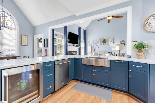 kitchen featuring lofted ceiling, blue cabinets, sink, wine cooler, and stainless steel dishwasher