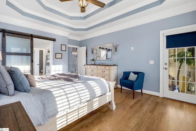 bedroom with a raised ceiling, a barn door, ceiling fan, and crown molding