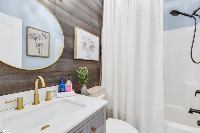 full bathroom featuring wood walls, shower / tub combo with curtain, vanity, and toilet