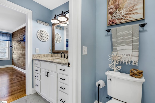 bathroom featuring wood-type flooring, vanity, ornamental molding, and toilet