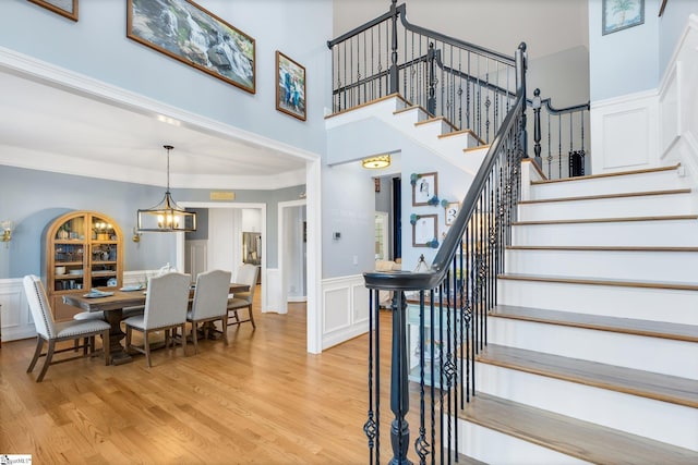 stairway featuring a chandelier, hardwood / wood-style floors, and ornamental molding