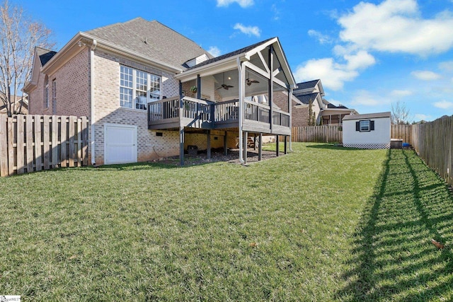 rear view of property featuring ceiling fan, a shed, a yard, and a wooden deck