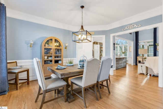 dining room with crown molding, light hardwood / wood-style flooring, and an inviting chandelier