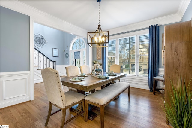 dining room with hardwood / wood-style flooring, ornamental molding, and a notable chandelier