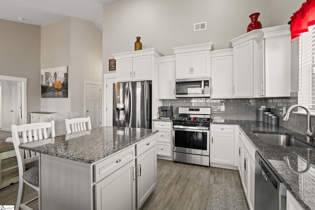 kitchen featuring white cabinetry, sink, a kitchen breakfast bar, tasteful backsplash, and appliances with stainless steel finishes