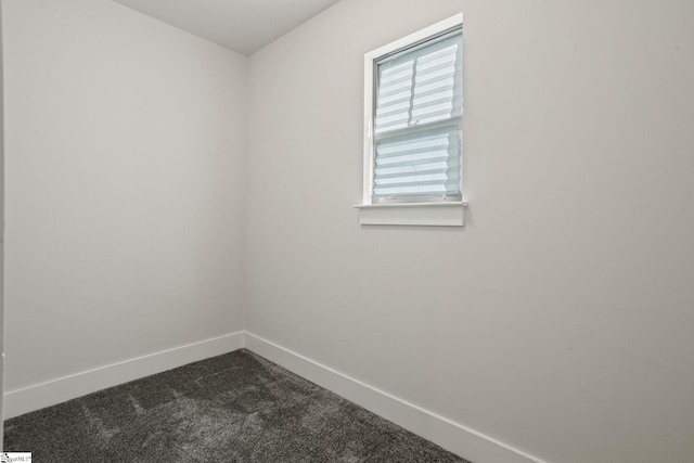 spare room featuring dark carpet