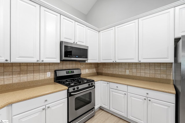 kitchen featuring white cabinets, decorative backsplash, lofted ceiling, and stainless steel appliances