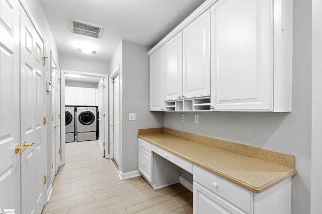 interior space with white cabinetry, built in desk, and independent washer and dryer