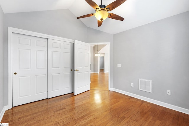 unfurnished bedroom featuring ceiling fan, light hardwood / wood-style floors, lofted ceiling, and a closet