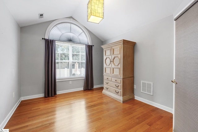 unfurnished bedroom with light wood-type flooring and lofted ceiling