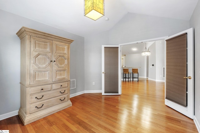 unfurnished bedroom featuring a chandelier, light hardwood / wood-style flooring, and vaulted ceiling