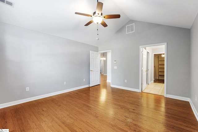 unfurnished bedroom with ceiling fan, a walk in closet, high vaulted ceiling, and light hardwood / wood-style flooring