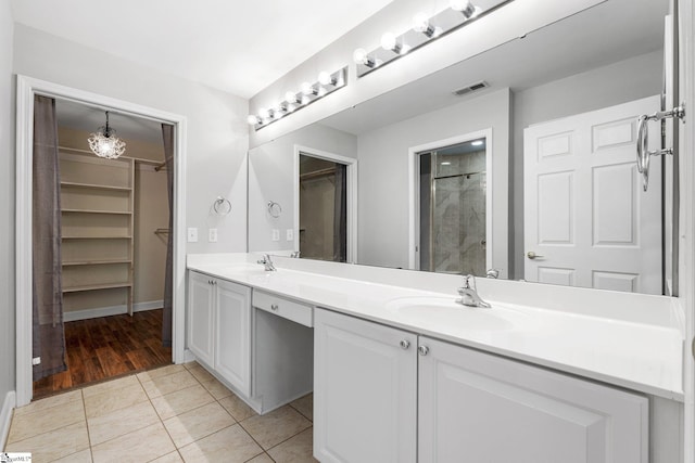 bathroom with tile patterned flooring, vanity, and tiled shower