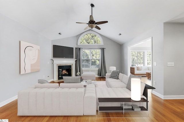 living room featuring a high end fireplace, wood-type flooring, ceiling fan, and lofted ceiling